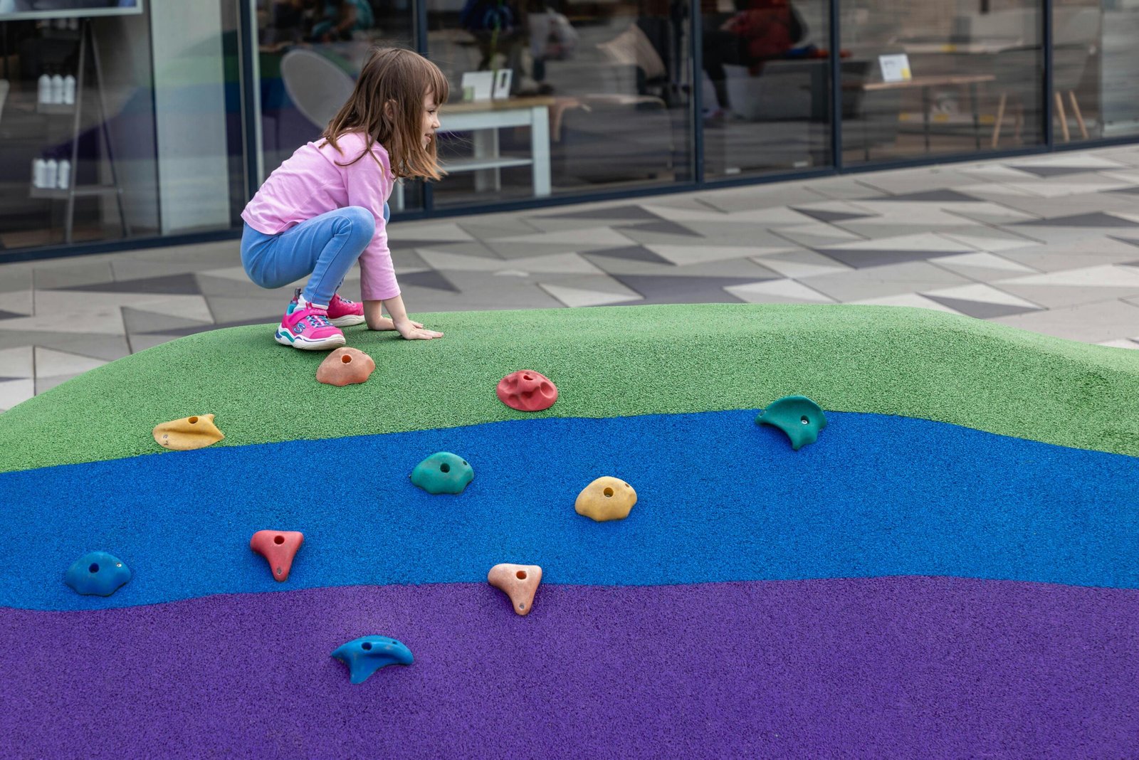 Young girl enjoying climbing a vibrant playground structure in Zagreb.